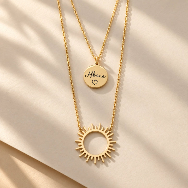 Collier double rang femme avec soleil ajouré doré et médaille ronde gravée sur chaîne fine, effet superposé
