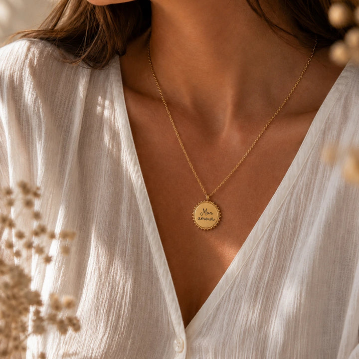 Collier femme médaille soleil dorée à bordure perlée porté sur décolleté, chaîne fine 47 cm